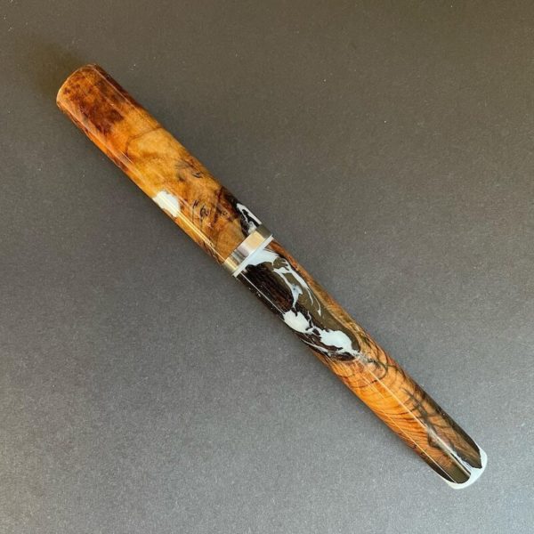 Pen capped showing gnarled wood interspersed with pale blue resin