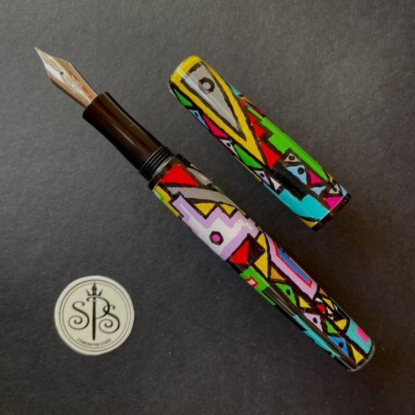 Uncapped fountain pen with a plain black grip section that accentuates the bright African patterns on the barrel and cap
