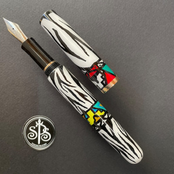 Pen with zebra stripes with a yellow and turquoise chevron design on barrel and red and turquoise chevrons on cap